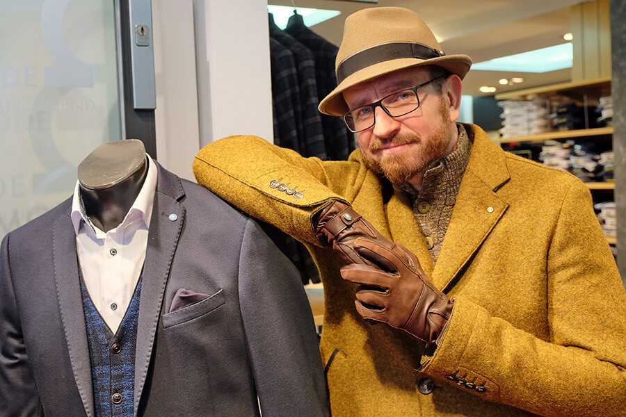 Männliches Model mit einem Mantel von Benvenuto und einem kuscheligen Pullover von Pierre Cardin.
